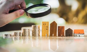 Money and apartments underneath a magnifying glass