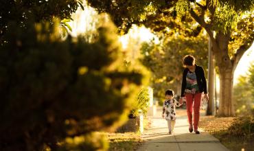 woman and child walking together on a sidewalk