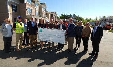 Group of people holding up a large check