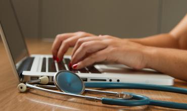 National Initiative Links Affordable Housing with Health Outcomes A stethoscope laying next to a person typing on a computer