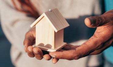 NC Homeowner Assistance Fund Helps More Than 10,000 Homeowners A person holding a small wooden house