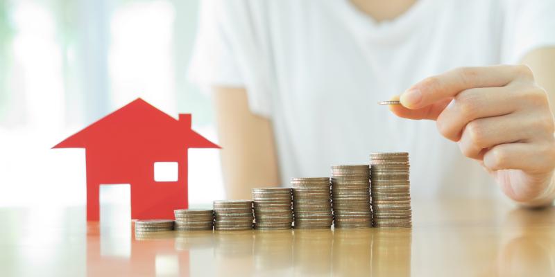 Beyond the Interest Rate:Three Important Numbers for First-Time Home Buyers an individual stacking coins next to a small model home