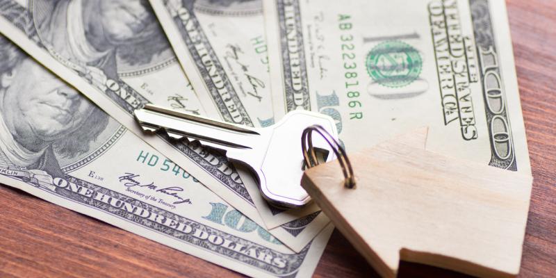 Funding Available Through Local Groups to Help Home Buyers Money with a key and wood house trinket on it