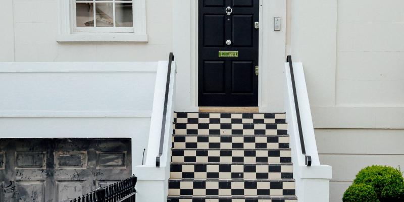 Little-Known Home Buying Resources A black house door above a checkerboard staircase