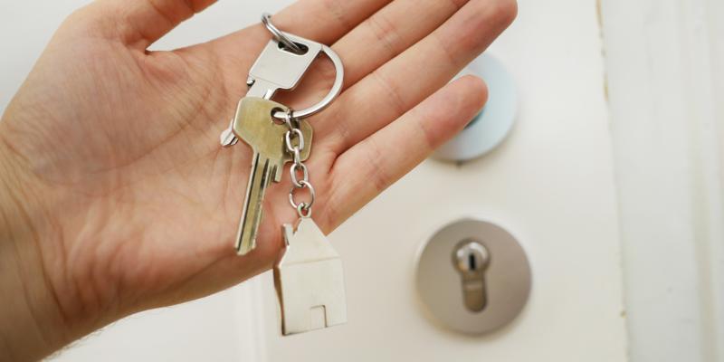 Unexpected Things that Might Not Come with Your Home A hand holding keys in front of a door