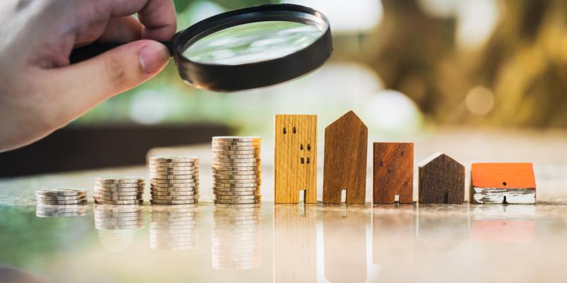 Report Credits LIHTC with Strong Track Record in Rural Persistent Poverty Counties apartments and coins with magnifying glass over them