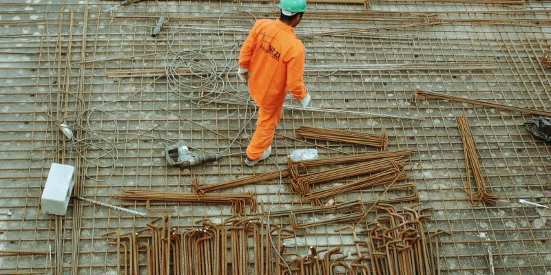 Hurricanes Harvey and Irma Strain Construction Supply A man in an orange suit walking a construction site
