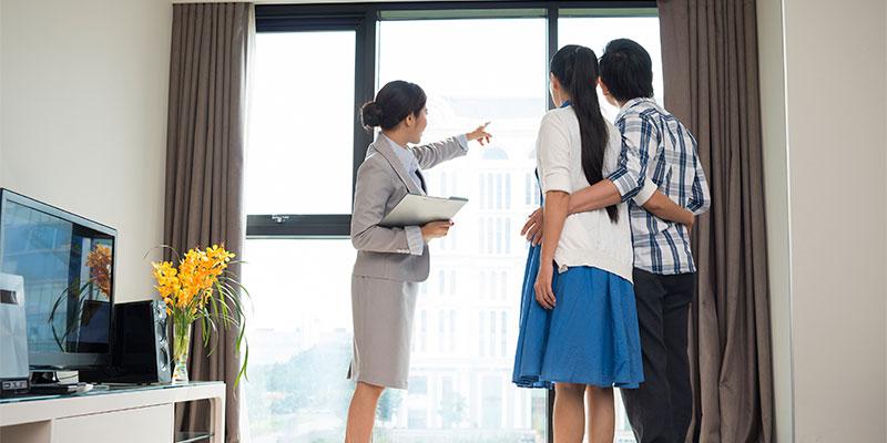 Financial Literacy Month: How to Avoid Being House Poor a realtor showing a couple the amenities of a new home