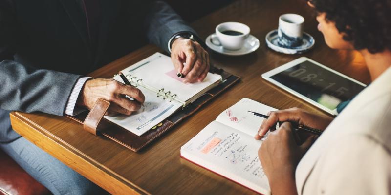 Unexpected Ways to Save for a Down Payment two people sitting at a desk doing finance work
